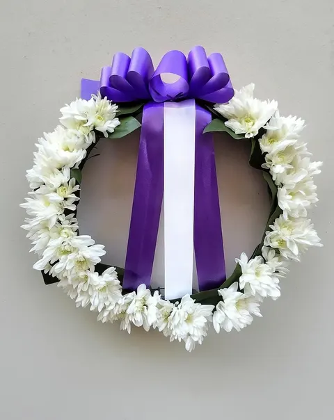 Funeral wreath with chrysanthemums and purple ribbon, elegant sympathy floral tribute for memorial and remembrance
