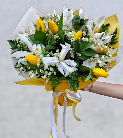 Vibrant tulip bouquet with mixed color tulips, white irises or alstroemeria and fresh greenery