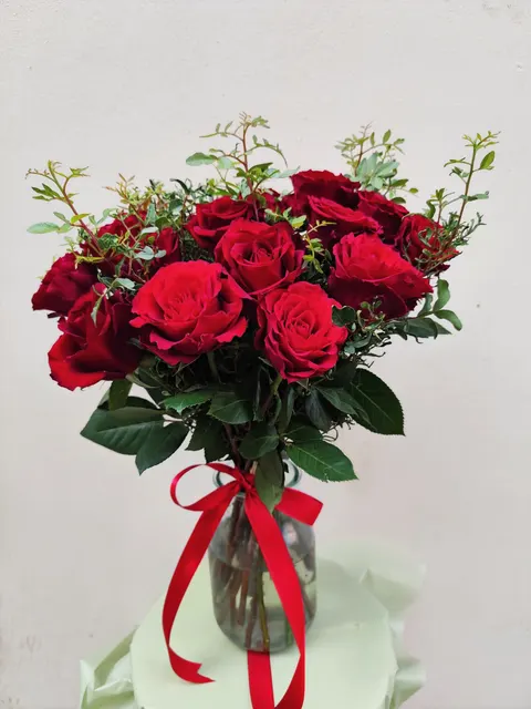 Elegant Roses Pistachio bouquet featuring 16 deep red roses with velvety petals and pistachio greenery